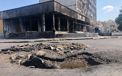 A crater caused by a Russian cruise missile  scars the street next to a shopping center in Vinnytsia where a strike killed 25 people, July 20, 2022 (Lazar Berman/The Times of Israel)