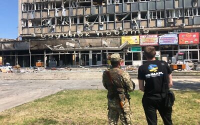 A Ukrainian soldier and civilian look at the shopping center in Vinnytsia where a Russian missile strike killed 25 people, July 20, 2022 (Lazar Berman/The Times of Israel)