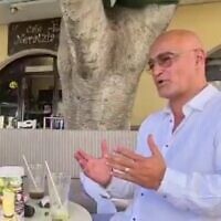 Dudi Ashkenazi at a cafe in Kos, Greece, in footage aired on July 6, 2022. (Screen capture/Channel 12)