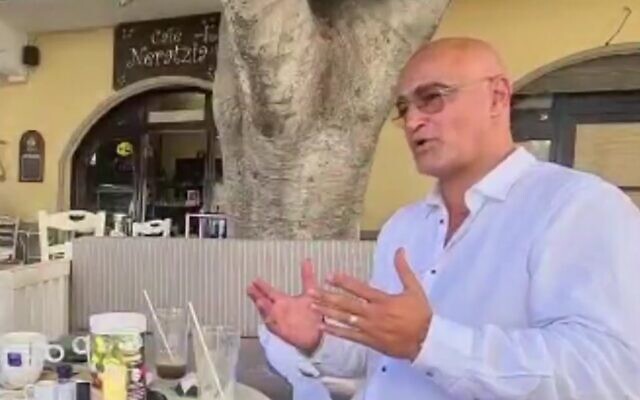 Dudi Ashkenazi at a cafe in Kos, Greece, in footage aired on July 6, 2022. (Screen capture/Channel 12)