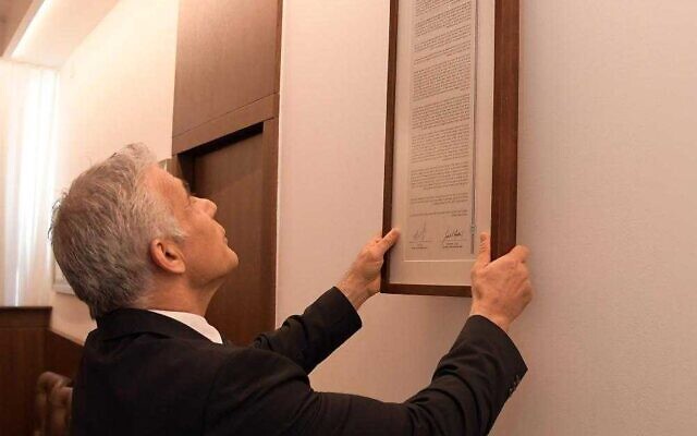 Prime Minister Yair Lapid hangs up the so-called Jerusalem Declaration sisnged by Israel and the US in the cabinet meeting room in Jerusalem, July 17, 2022 (Haim Zach/GPO)