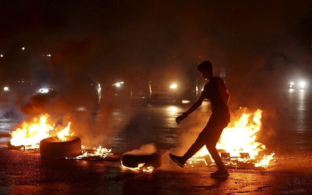 A Palestinian demonstrator kicks a burning tyre as protesters block the main street near the Hawara checkpoint, south of Nablus, to protest against the Israeli air strikes in Gaza. (JAAFAR ASHTIYEH / AFP)
