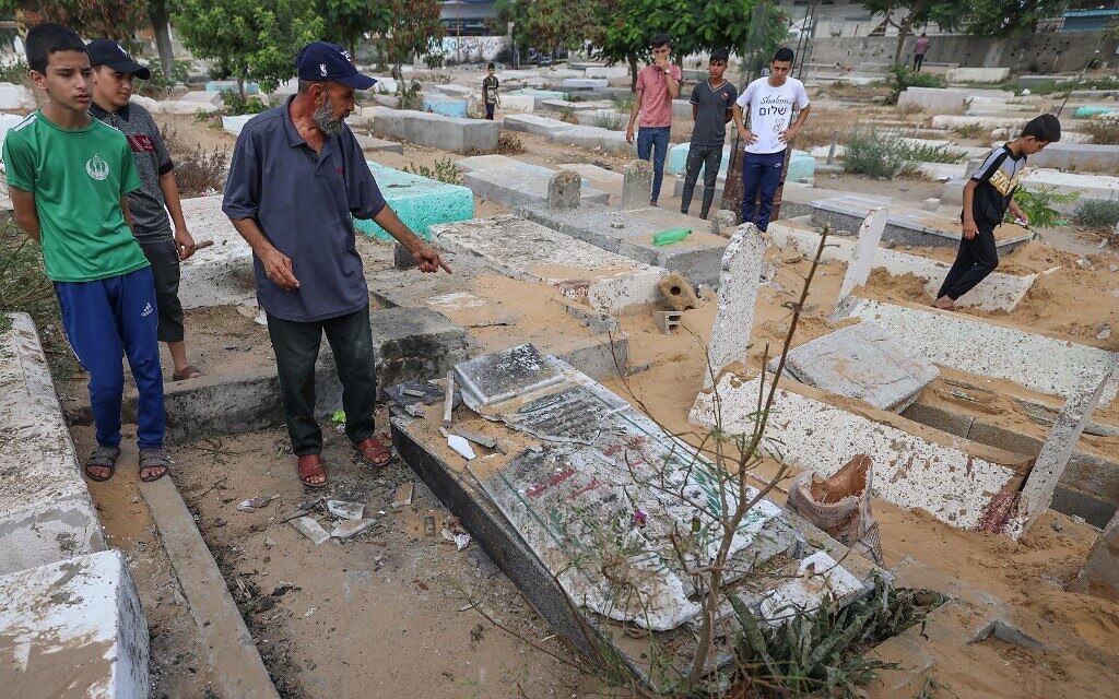 A Palestinian man inspects a cemetery which was damaged  during fighting at the Jabaliya refugee camp in the northern Gaza Strip, on August 8, 2022. The man's white T-shirt says the word 'Shalom,' or 'Peace' in Hebrew (MOHAMMED ABED / AFP)