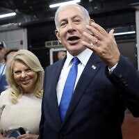 Likud party leader and former prime minister Benjamin Netanyahu gestures after voting next to his wife Sara in a primary to fill out the party's Knesset slate, in Tel Aviv on August 10, 2022. (GIL COHEN-MAGEN / AFP)