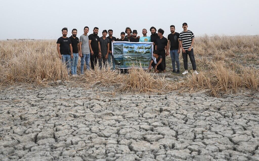 Demonstrators lift a banner with a slogan in Arabic which reads "Save the marshes, water scarcity is killing life in the marshes" as they rally at the Umm El Wadaa marsh, south-east of the city of Nasiriyah in Iraq's southern Dhi Qar province, on August 16, 2022, to demand solutions for water scarcity and drought. (Asaad NIAZI / AFP)