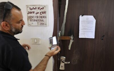A man photographs an Israeli military order on the closed door of Defense for Children-International in Palestine, after it was raided by Israeli forces in the West Bank city of Ramallah for alleged terror links, on August 18, 2022. (Abbas Momani/AFP)