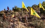 Hezbollah fighters pose with the terror group's flags (yellow) and flags bearing the names of venerated Shiite Muslim figures (black) during a ceremony to lay the foundation for a site for 'jihadist tourism,' at a camp formerly run by Iran's Islamic Revolutionary Guard Corps in Lebanon to train Hezbollah fighters, in the Janta region in the east of the country, on August 19, 2022. (AFP)