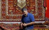 Iranian artisan works during the 29th Handmade Carpet Exhibition in Iran's capital Tehran on August 23, 2022 (AFP)
