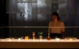 British museum press assistant Stella Scobie examines the newly conserved ancient glass vessels damaged during the 2020 Beirut port explosion, and displayed at the British Museum in London, on August 24, 2022 (Susannah Ireland/AFP)