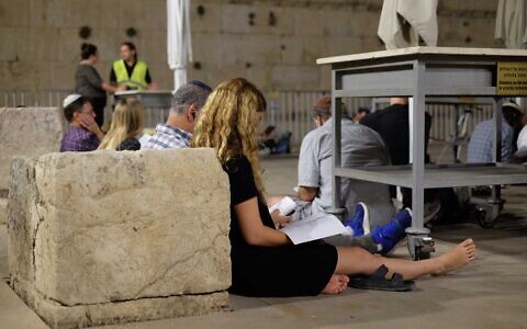 People gather to hear a reading of the Book of Lamentations at the egalitarian section of the Western Wall on August 6, 2022. (Judah Ari Gross/Times of Israel)