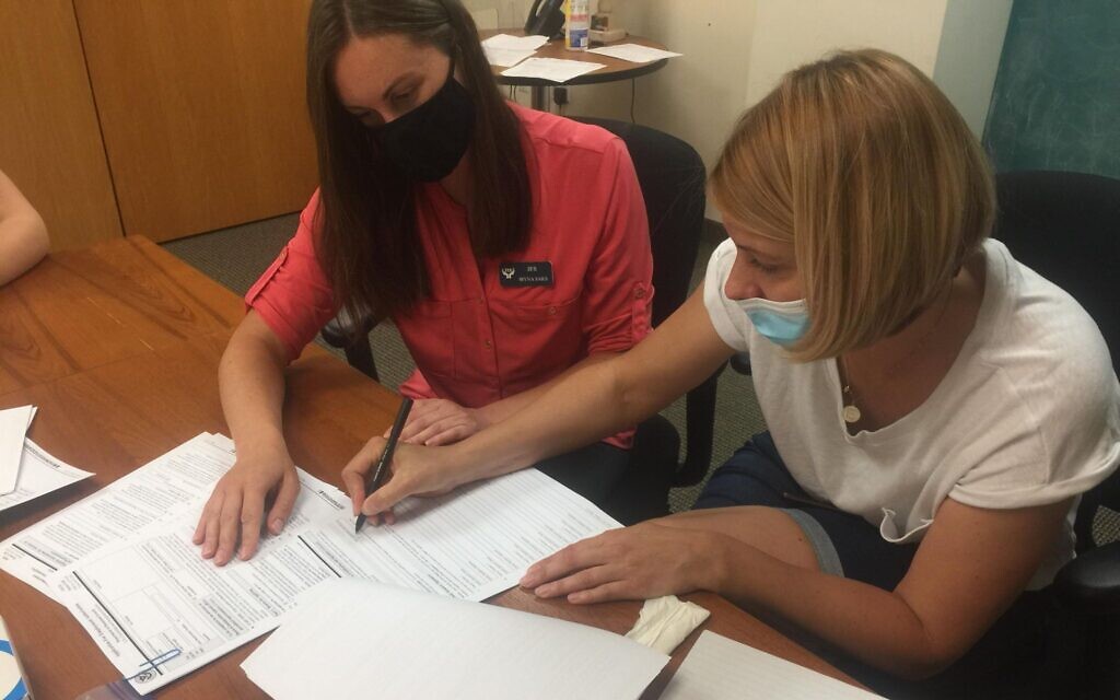 Olena Mironyuk, right, signs paperwork with the help of staff member Iryna Saks at the Jewish Family Service office in Framingham, Massachusetts. (Courtesy)
