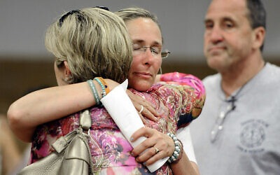 In this July 11, 2013, photo, Scarlett Lewis, center, mother of Sandy Hook Elementary School shooting victim Jesse Lewis, hugs Lynn McDonnell, left, mother of victim Grace McDonnell, as Neil Heslin, right, father of Jesse Lewis watches after a public forum in Newtown, Connecticut. (AP Photo/Jessica Hill)