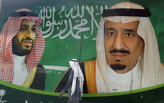 In this March 7, 2020, file photo, a man walks past a banner showing Saudi King Salman, right, and his Crown Prince Mohammed bin Salman, outside a mall in Jiddah, Saudi Arabia. (AP Photo/Amr Nabil, File)