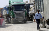 Illustrative: A Hamas security officer checks trucks carrying materials that are waiting to enter Gaza, at the Kerem Shalom cargo crossing with Israel, in Rafah, southern Gaza Strip, September 1, 2021. (AP Photo/Adel Hana)