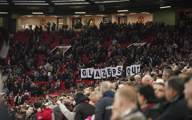 Manchester United supporters hold a banner reading 'Glazers Out' on the stands during the English Premier League soccer match between Manchester United and Chelsea, at Old Trafford Stadium, Manchester, England, Thursday, April, 2022. (AP Photo/Dave Thompson)