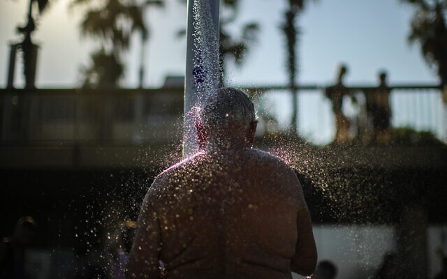 A man cools off in a public shower at a beach during a hot, sunny day in Barcelona, Spain, July 21, 2022. (AP Photo/ Francisco Seco)
