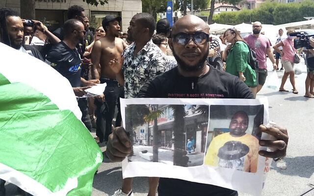 A man shows a picture of the victim Nigerian street vendor Alika Ogorchukwu, in Civitanova Marche, Italy, July 30, 2022. (AP/Chiara Gabrielli)