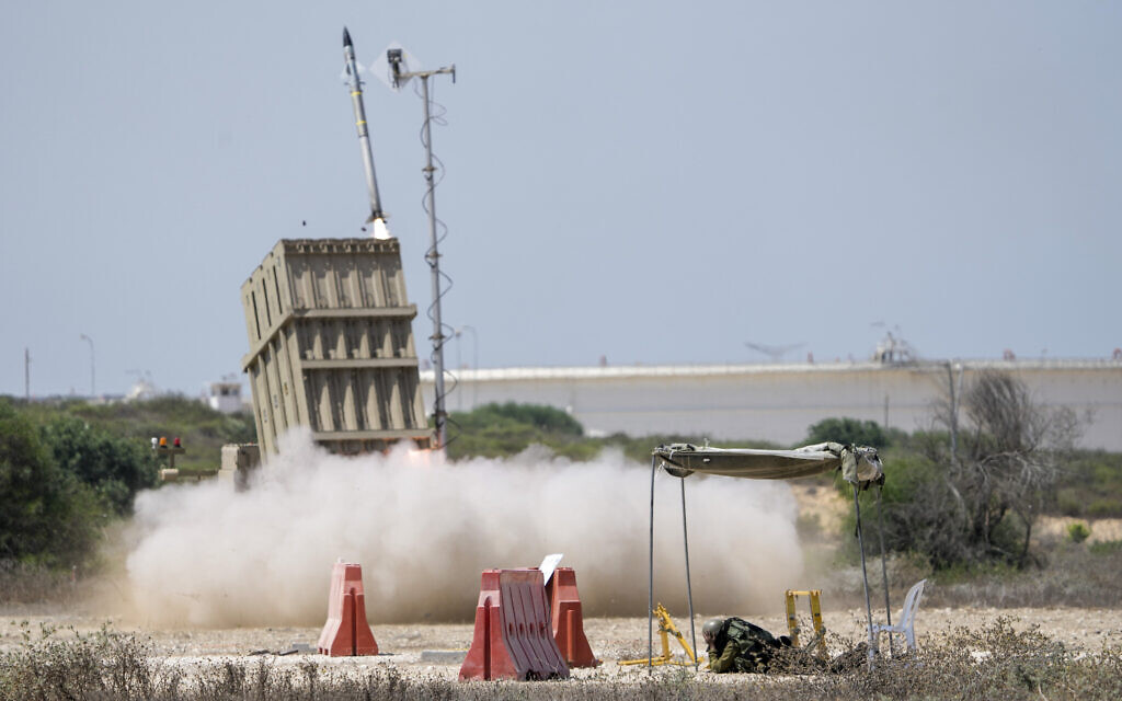 An Israeli soldier takes cover as an Iron Dome air defense system launches to intercept a rocket fired from the Gaza Strip, in southern Israel, Aug. 7, 2022. (AP Photo/Ariel Schalit)