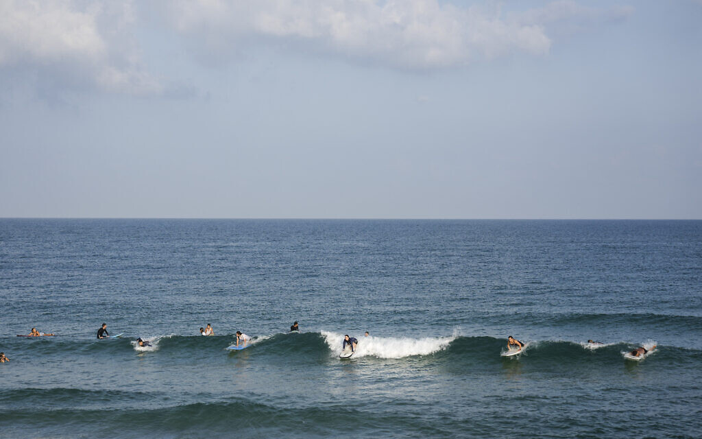 Surfers enjoy the early morning in the Mediterranean Sea off the southern coastal city of Ashkelon on August 8, 2022, following a ceasefire between the Israel and Gaza-based Palestinian Islamic Jihad. (AP Photo/Ariel Schalit)
