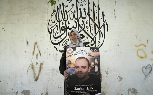 File: Dalal Awawdeh poses with a poster of her husband Khalil Awawdeh, at their home in the West Bank village of Idna, Hebron, August 9, 2022. (AP Photo/Nasser Nasser)