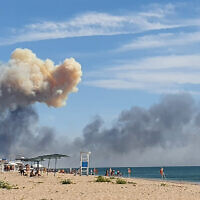 Rising smoke can be seen from the beach at Saky after explosions were heard from the direction of a Russian military airbase near Novofedorivka, Crimea, Aug. 9, 2022. (UGC via AP)