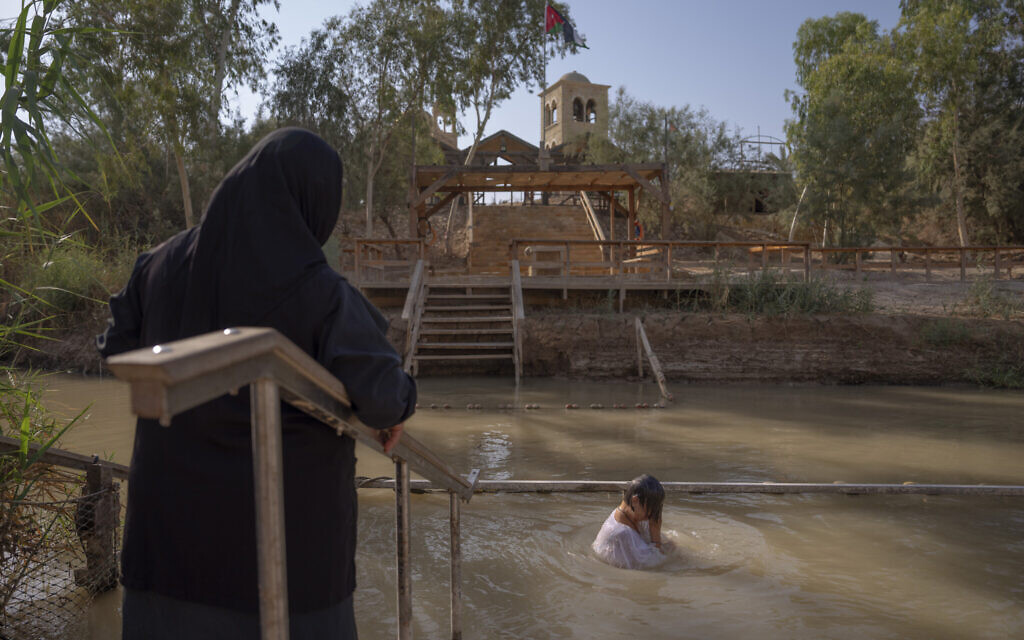 Olga Bokkas, a visitor from Connecticut, immerses herself in the waters of the Jordan River at the Qasr al-Yahud baptismal site, near the West Bank town of Jericho on Sunday, July 31, 2022. The river’s dwindling waters are sluggish and a dull brownish green in this area. (AP Photo/Oded Balilty)