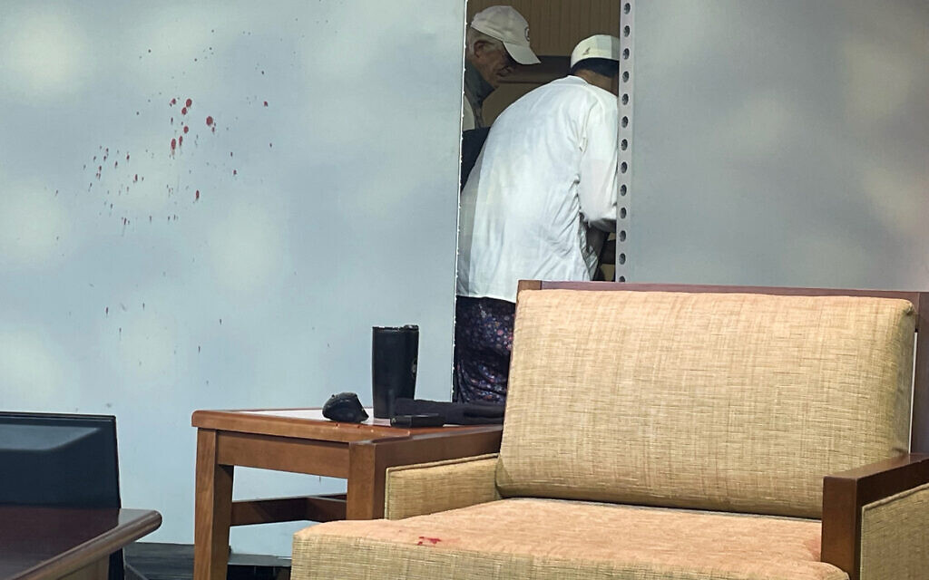 Blood stains mark a screen as author Salman Rushdie, behind screen, is tended to after he was attacked during a lecture, Friday, August 12, 2022, at the Chautauqua Institution in Chautauqua, NY. (AP Photo/Joshua Goodman)