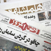The front pages of the Iranian newspapers, Vatan-e Emrooz, front, with title reading in Farsi: "Knife in the neck of Salman Rushdie," and Hamshahri, rear, with title: "Attack on writer of Satanic Verses," are pictured in Tehran, August 13, 2022. (AP Photo/Vahid Salemi)