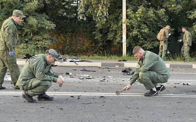In this handout photo taken from video released by Investigative Committee of Russia on August 21, 2022, investigators work on the site of explosion of a car driven by Daria Dugina outside Moscow. (Investigative Committee of Russia via AP)