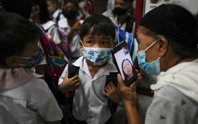A boy talks to his mother from a smartphone during the opening of classes at the San Juan Elementary School in metro Manila, Philippines on Monday, August 22, 2022. Millions of students wearing face masks streamed back to grade and high schools across the Philippines Monday in their first in-person classes after two years of coronavirus lockdowns that are feared to have worsened one of the world's most alarming illiteracy rates among children. (AP Photo/Aaron Favila)