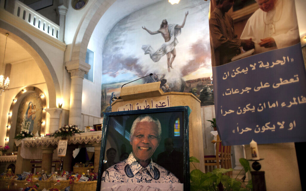 Pictures of late South African leader Nelson Mandela are seen during a special service in his honor at the Holy Family Church in the West Bank city of Ramallah, December 8, 2013. (AP Photo/Nasser Nasser)