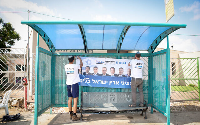 Activists put up a poster for the Likud primaries in Safed, August 10, 2022 (David Cohen/FLASH90)