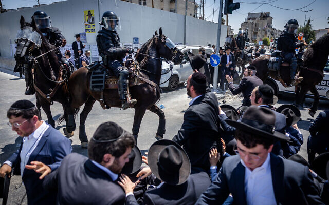 Police scuffle with ultra-Orthodox men in the Jerusalem neighborhood of Ramot on August 15, 2022, during a protest over the autopsy of a 4-year-old boy who was allegedly strangled to death by his uncle a few days before. (Yonatan Sindel/Flash90)