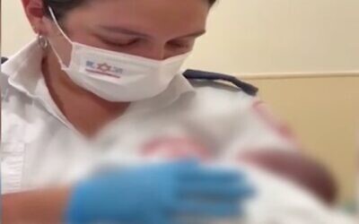 Screen capture from video of MDA medic Monay Jamal with a newborn baby found abandoned on a street in Acre, August 8, 2022. (Channel 12)