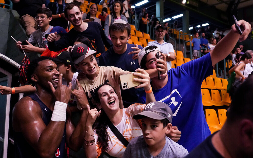 Chris Moore, left, a forward for Auburn University's basketball team, takes a selfie with fans during a game against the Israeli national under-20 basketball squad, in Malha Arena, Jerusalem, August 2, 2022. (Steven Leonard/Auburn University)