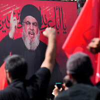 File: Hezbollah terror leader Hassan Nasrallah speaks via a video link, as his supporters raise their hands, during the Shiite holy day of Ashoura, in a southern suburb of Beirut, Lebanon, August 9, 2022. (AP Photo/Hussein Malla)