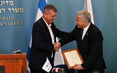 Prime Minister Yair Lapid (R) shakes hands with the incoming director general of Israel's Atomic Energy Commission, Moshe Edri, August 1, 2022. (Haim Zach/GPO)