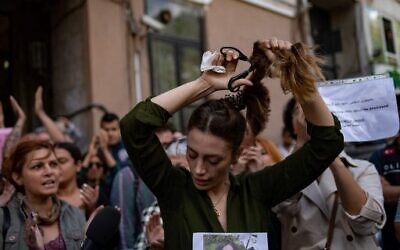 Nasibe Samsaei, an Iranian woman living in Turkey, cuts her ponytail off during a protest outside the Iranian consulate in Istanbul on September 21, 2022, following the death of an Iranian woman after her arrest by the country's morality police in Tehran. (Yasin AKGUL / AFP)