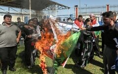 People burn an Iranian national flag during a demonstration denouncing the death of 22-year-old Mahsa Amini -- who died while in the custody of Iranian authorities -- by Iraqi and Iranian Kurds outside the UN offices in Arbil, the capital of Iraq's autonomous Kurdistan region, on September 24, 2022. (Safin Hamed/AFP)