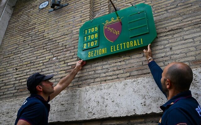 Police officers put up an official identification board on September 24, 2022 outside a polling station in Rome, on the eve of the country’s legislative election. (Andreas Solaro/AFP)