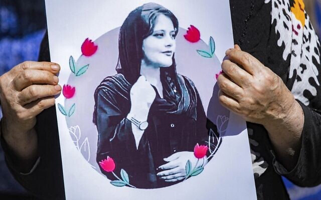 A woman holds up a sign depicting a picture of 22-year-old Mahsa Amini, an Iranian woman who died while in the custody of Iranian authorities, during a solidarity demonstration in Syria's northeastern city of Hasakeh on September 25, 2022. (Delil Souleiman/AFP)