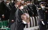 The widow of former Japanese prime minister Shinzo Abe, Akie Abe (C), carries his ashes as she arrives for the start of his state funeral at the Nippon Budokan in Tokyo on September 27, 2022. (Philip Fong/Pool/AFP)