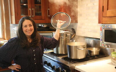 Shannon Sarna, author of 'Modern Jewish Comfort Food,' stands over a pot of chicken soup, one of the many comfort food recipes in her new book. (Doug Schneider/via JTA)