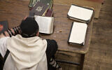 Jewish man wearing tefillin and reading religious text. (Getty Images)