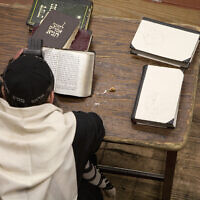 Jewish man wearing tefillin and reading religious text. (Getty Images)