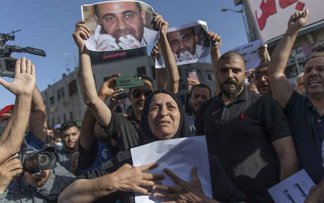 Maryam Banat, 67, mother of Palestinian Authority outspoken critic Nizar Banat holds a poster with his picture while attending a rally protesting his death, in the West Bank city of Ramallah, Saturday, July 3, 2021. (AP Photo/Nasser Nasser)