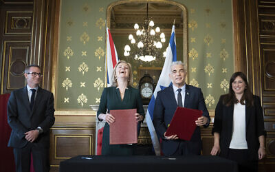 Foreign Secretary Liz Truss, center left, and Israeli Foreign Minister, Yair Lapid, center right, sign a memorandum of understanding at the Commonwealth And Development Office in London watched by the British Ambassador to Israel, Neil Wigan, left, and Israeli Ambassador to the United Kingdom, Tzipi Hotovely, right, where they held meetings and a news conference to discuss closer collaboration between the UK and Israel, in London, November 29, 2021. (Stefan Rousseau/Pool via AP)