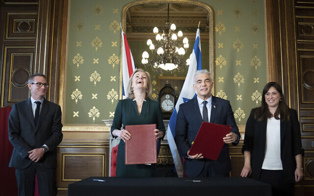 Foreign Secretary Liz Truss, center left, and Israeli Foreign Minister, Yair Lapid, center right, sign a memorandum of understanding at the Commonwealth And Development Office in London watched by the British Ambassador to Israel, Neil Wigan, left, and Israeli Ambassador to the United Kingdom, Tzipi Hotovely, right, where they held meetings and a news conference to discuss closer collaboration between the UK and Israel, in London, November 29, 2021. (Stefan Rousseau/Pool via AP)
