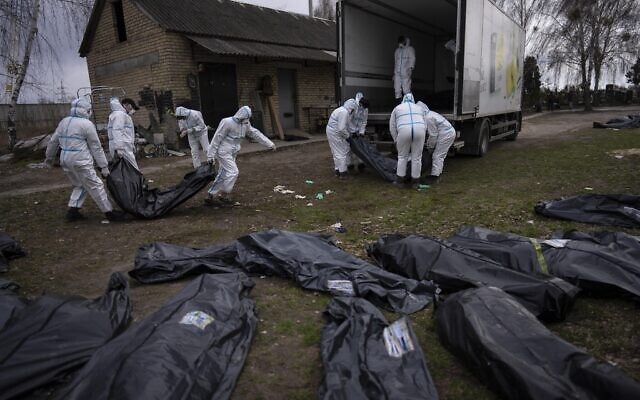 Volunteers load on a truck corpses of civilians killed in Bucha to be taken to a morgue for investigation, in the outskirts of Kyiv, Ukraine, April 12, 2022. (Rodrigo Abd/AP)