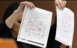 Judge Elizabeth Scherer holds up documents as she considers arguments from the defense that the jury should be prevented from seeing the swastikas on the pages (circled in red) during the trial of Marjory Stoneman Douglas High School shooter Nikolas Cruz at the Broward County Courthouse in Fort Lauderdale, Fla., on Thursday, Sept. 1, 2022. (Amy Beth Bennett/South Florida Sun-Sentinel via AP, Pool)